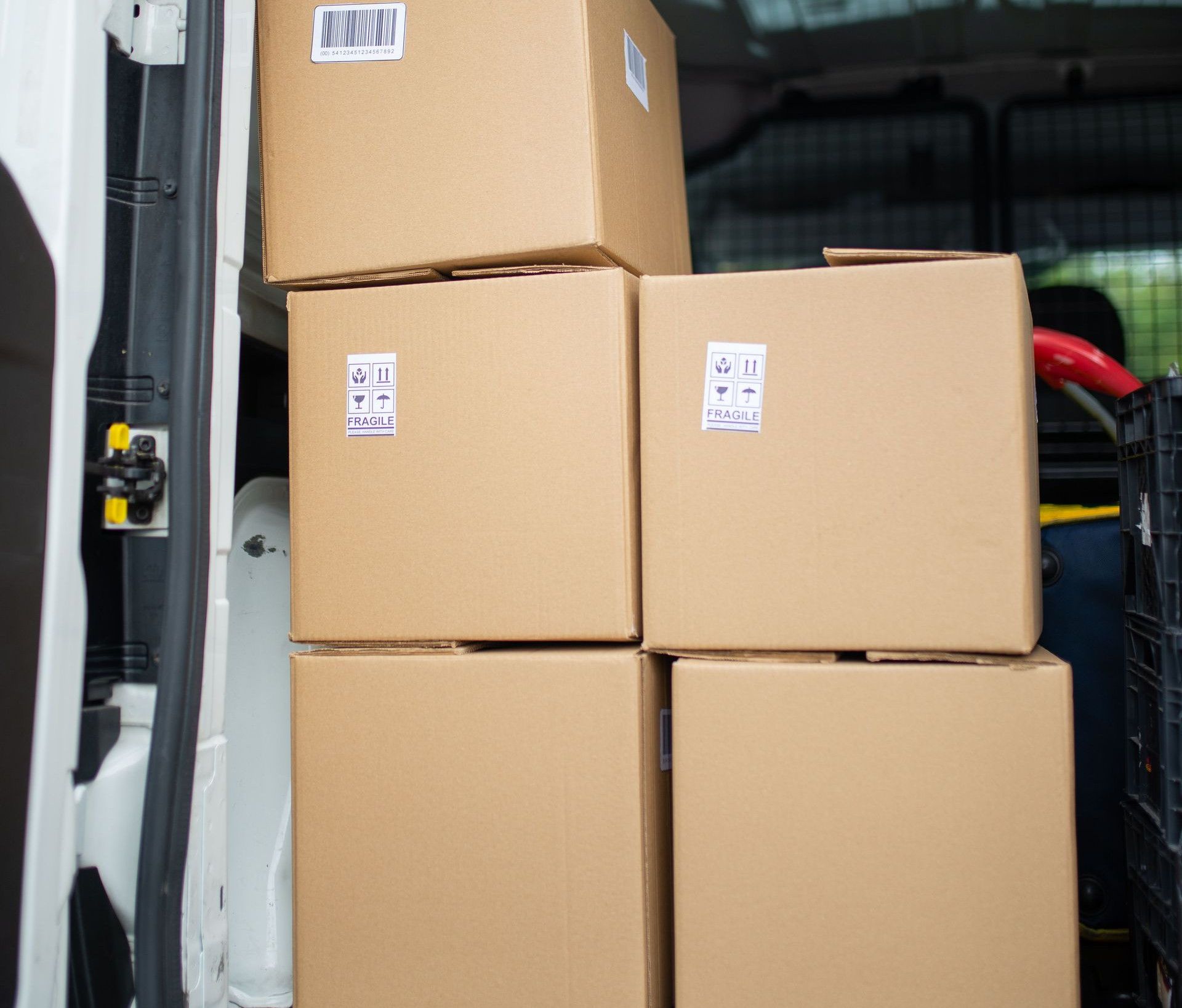 Stacked cardboard boxes inside an open delivery van, ready for shipment.